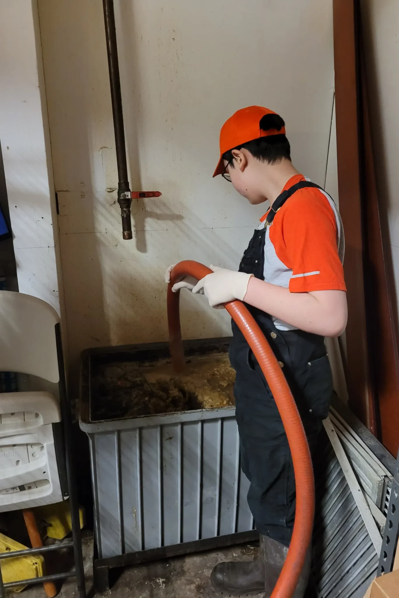 Technician using a suction hose to clean out a grease trap full of grease